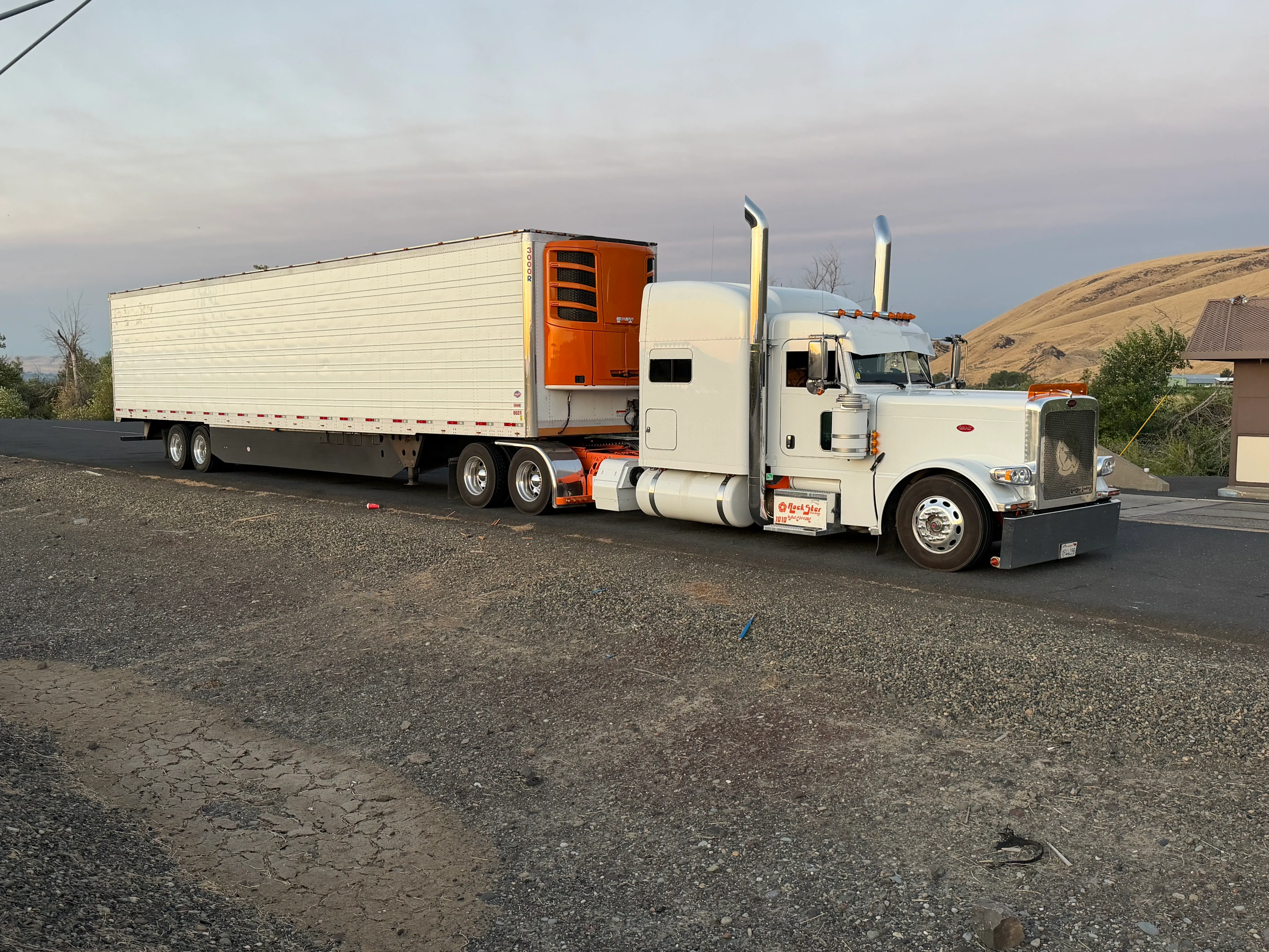Rockstar Trucking rig with reefer trailer on the road at dusk in Northern California hills